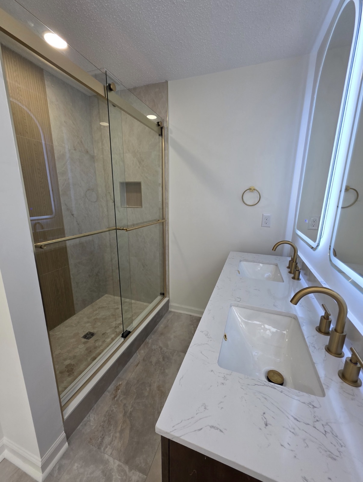 A renovated bathroom with a glass shower and double vanity